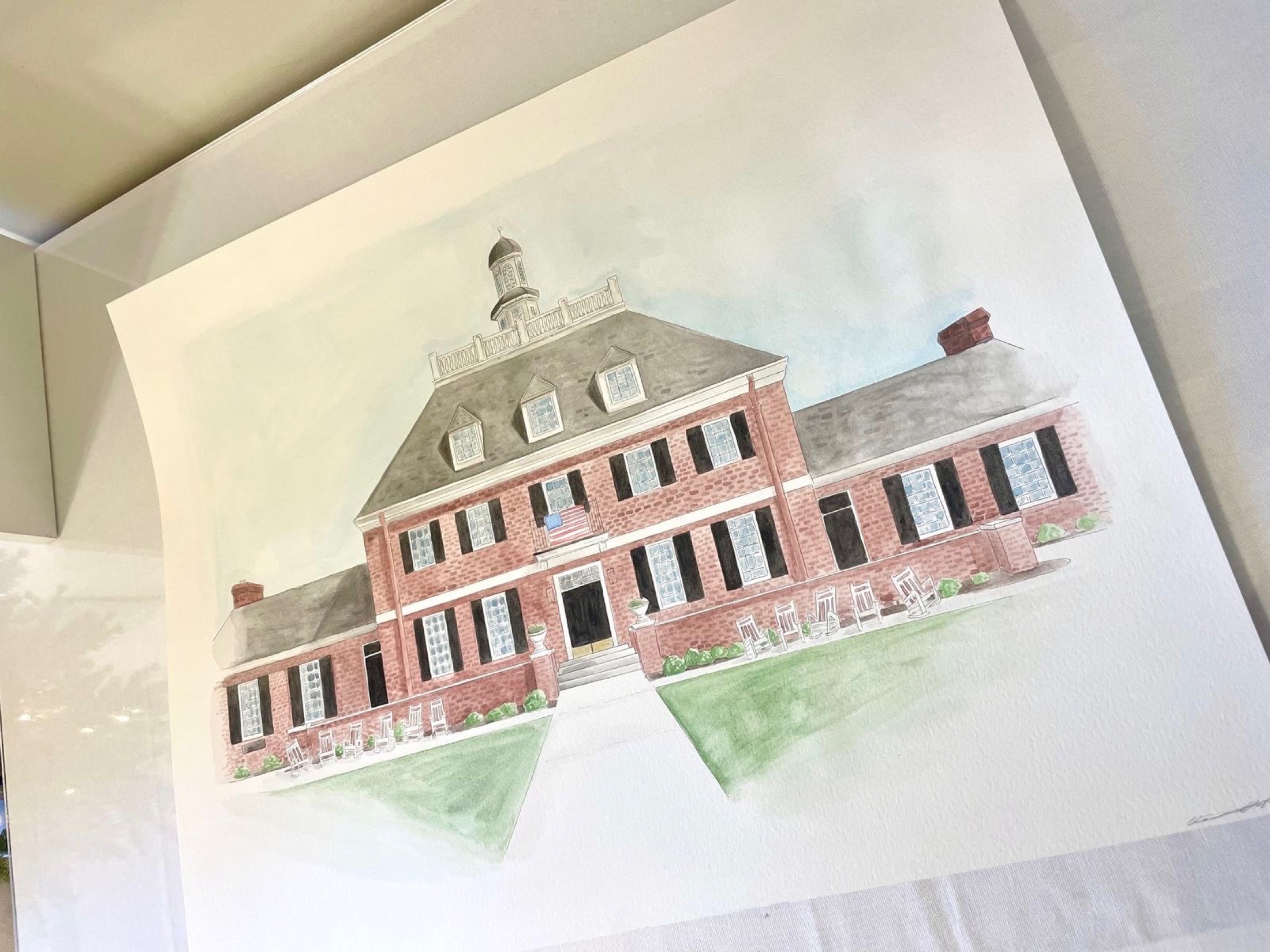 A detailed watercolor portrait of a brick building presented on paper