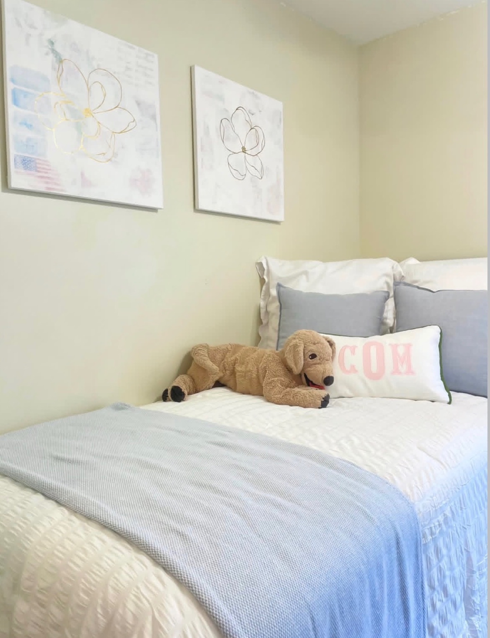 Two soft floral paintings installed above a serene blue and white bed