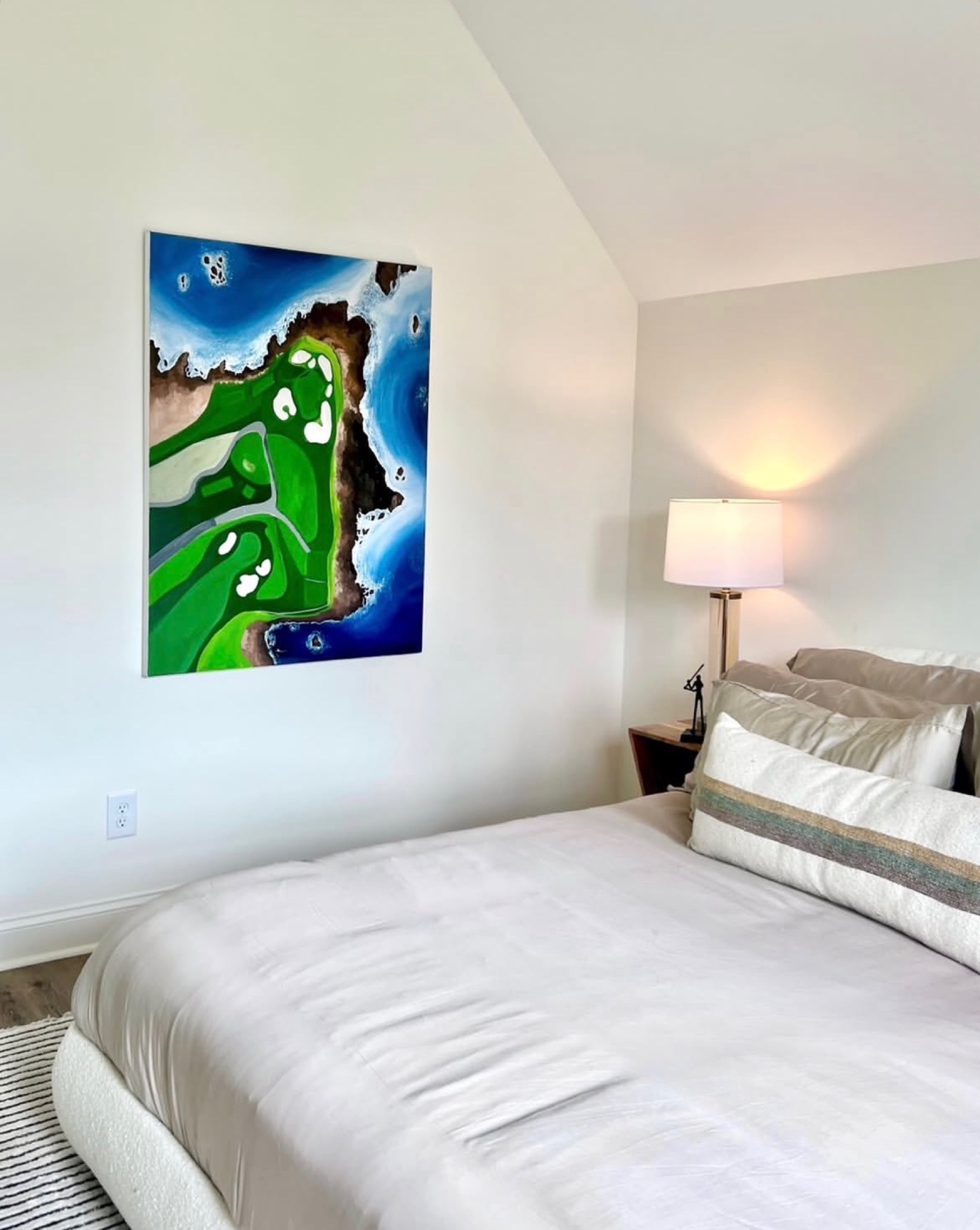A colorful golf-course painting installed in a calm bedroom